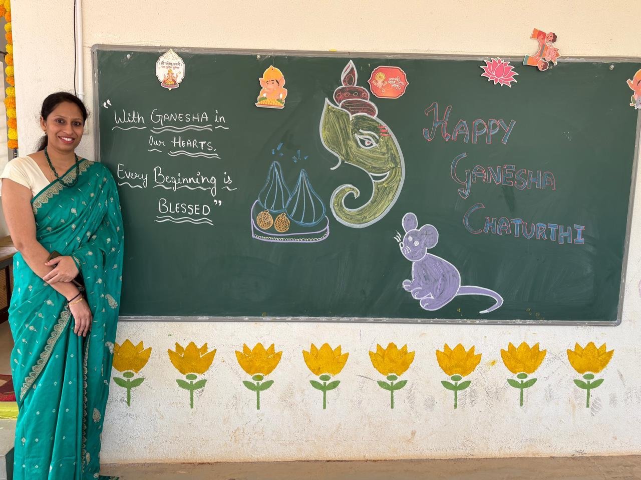 Arka educator beside the Ganesha Chaturthi classroom artwork