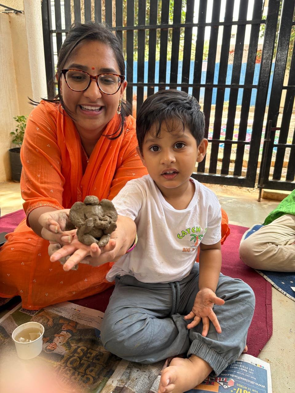 A child and educator sharing a handmade Ganesha during the festival