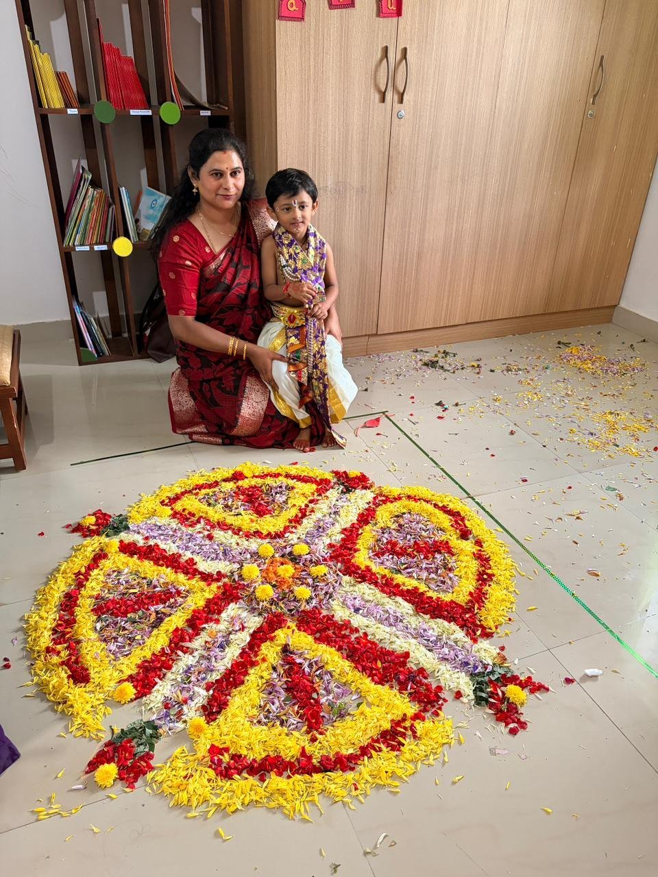 A child and adult beside Arka's Onam flower pookalam